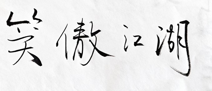 Chinese calligraphy on paper reading '笑傲江湖' (Xiao Ao Jiang Hu, meaning 'Laughing Proud in the Jianghu') in expressive brushstrokes.
