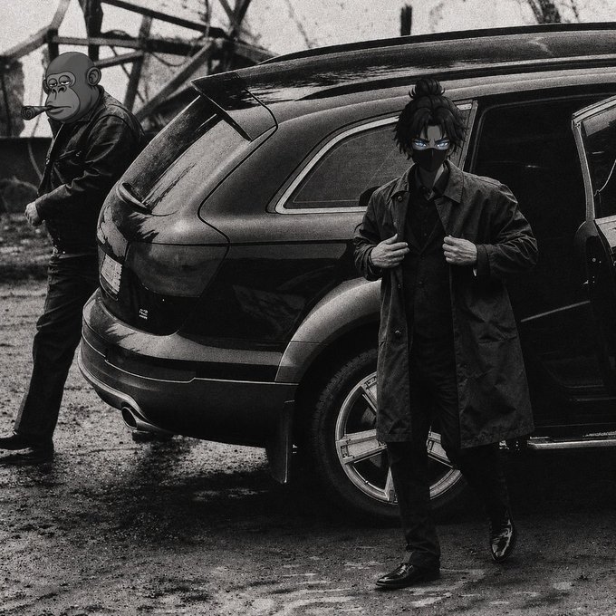 A black and white photo of two men wearing masks standing next to a dark SUV, with one adjusting his long coat in what appears to be an industrial setting.