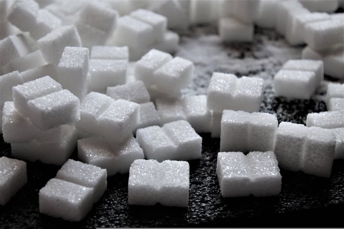 A close-up shot of white sugar cubes scattered across a dark surface, visually representing the newly launched $SUGAR token, which the post introduces as the essential sweet complement to the $GARRI token. The accompanying text highlights the playful concept that "every good Garri needs a little sweetness," tying the image's sugar cubes directly to the meme coin's branding.