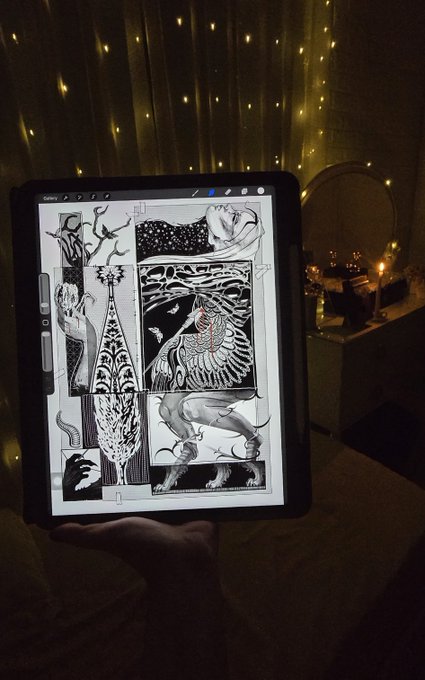 A hand holds a tablet displaying black and white illustrations of birds and trees, with warm fairy lights visible in the background.