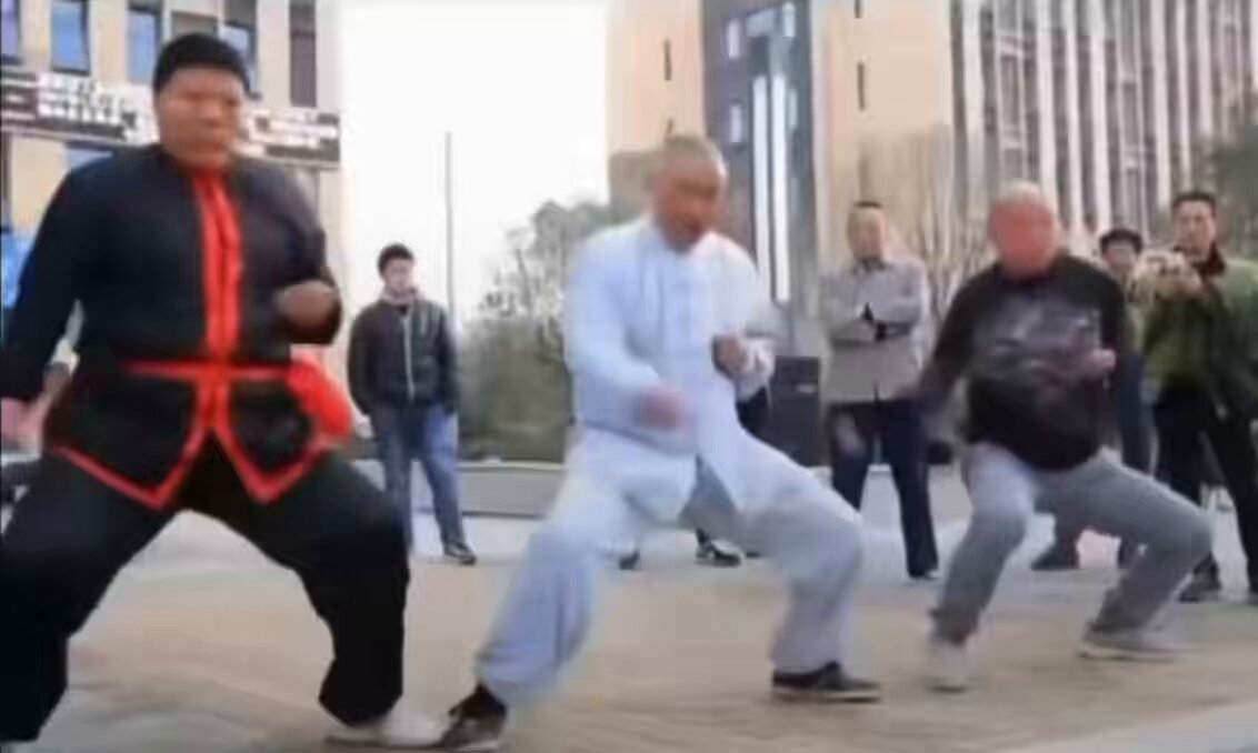 The image shows a group of people performing Tai Chi moves, with two men wearing white outfits and one man dressed in black. The other participants are also wearing similar attire. They appear to be practicing together as part of an event or gathering. In the background, there is a building visible behind them, suggesting that they might be taking place in an urban setting. The post about the investors preparing for the rest of 2026 indicates that this gathering could potentially be related to a financial event or milestone celebration.