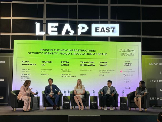 A panel discussion on the 'Orbital Stage' at LEAP EAST with five speakers, under the title 'TRUST IS THE NEW INFRASTRUCTURE: SECURITY, IDENTITY, FRAUD & REGULATION AT SCALE', featuring panelists Alina Timofeeva, Tianwei Liu, Petra Janez, Takatoshi Shibayama, and Yoyee Wang.
