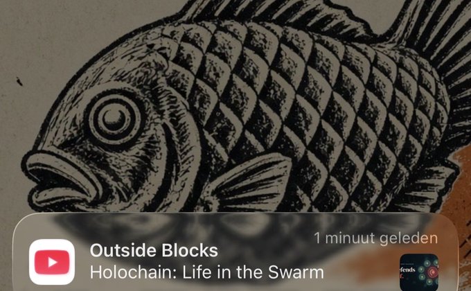 A YouTube video notification from the channel "Outside Blocks" titled "Holochain: Life in the Swarm" with a "1 minuut geleden" timestamp, overlaid on an illustration of a fish.