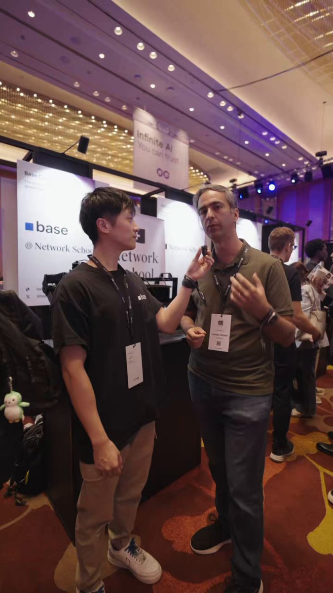 The image features two people standing next to each other in a large room with an indoor arcade theme. They appear to be discussing something or simply interacting with one another. The background of the image reveals that there are multiple game booths and displays, which suggests that this event might be related to gaming or technology. In the text accompanying the image, it is mentioned that Coinbase has built an x402 for the next generation of agentic payments, which may have some connection to the indoor arcade setting.