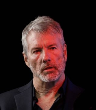 The image shows a middle-aged man with gray hair and a beard, wearing a dark suit jacket against a black background, with red lighting casting a dramatic tone across his face.

The image appears to depict a somber or concerned-looking figure, fittingly illustrating the post's news that Strategy (formerly MicroStrategy) has sold $108.6M in Bitcoin, contributing to BTC's recent price decline after $431.6M in sales over two months.