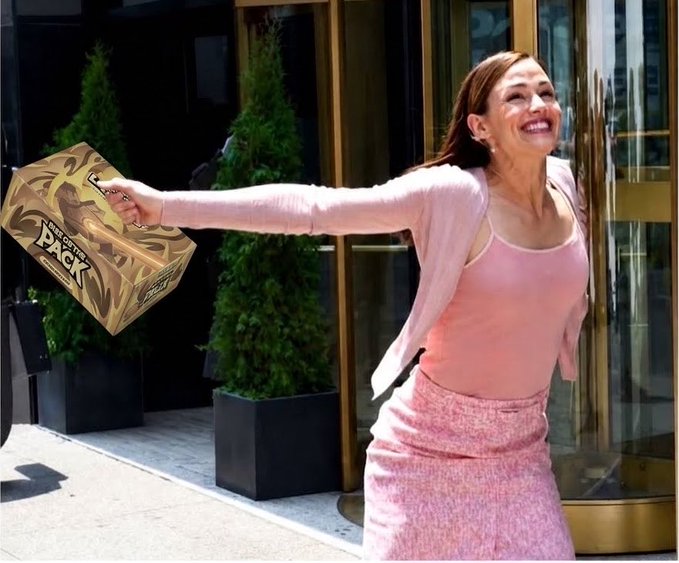A woman in a pink tank top and pink skirt smiles joyfully with arms outstretched while holding a gold-wrapped package labeled "Miracle Fruit Party Pack" outside a building.