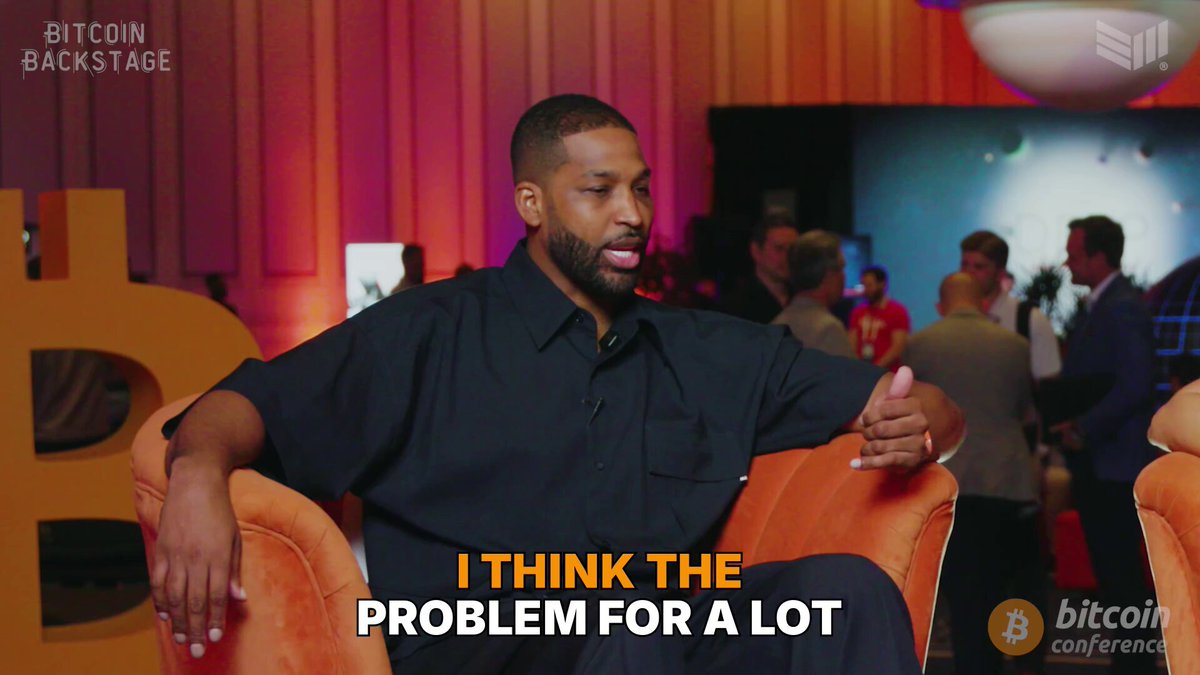 The image features a man sitting in an orange chair, wearing a black shirt, and holding up his hand with a thumbs-up gesture. The background shows a room filled with people, suggesting that this event might be taking place at a Bitcoin conference or gathering. The main focus of the image is on the man's face, which reads "I think the problem for a lot". This statement seems to be related to the post about Bitcoin and its impact on finance.