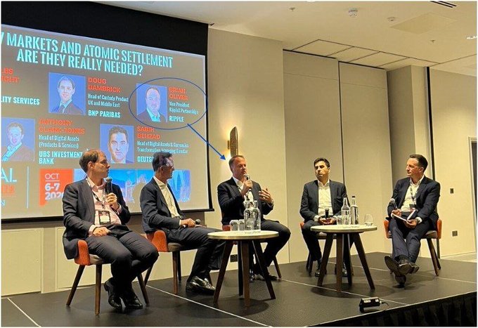 A panel discussion titled 'MARKETS AND ATOMIC SETTLEMENT ARE THEY REALLY NEEDED?' featuring speakers including Doug Damrick from BNP Paribas and Dmitrij Radin from Ripple.