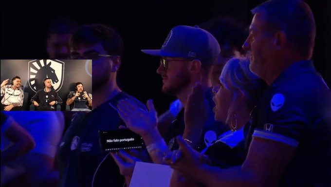 Audience members wearing Liquid-branded jerseys clap at an esports event, while an inset video shows a team of players on a stage with a Liquid logo.