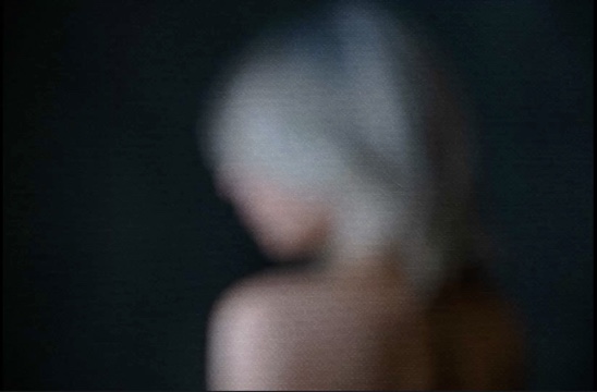 A heavily blurred, dark image showing an indistinct figure.