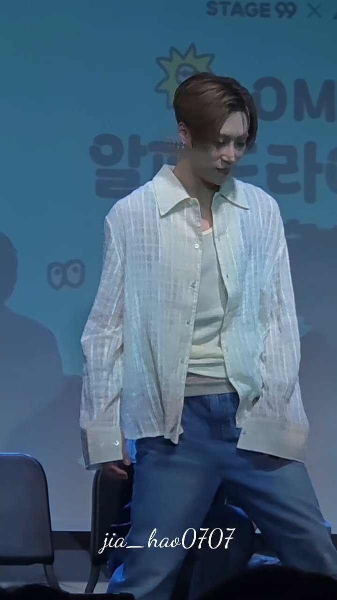The image features a man wearing a white shirt and blue jeans standing next to chairs, with his legs crossed. The background of the photo shows a stage setup with a banner that reads "Stage 99 Chains". The caption at the bottom of the image provides information about the person in the picture, stating that they are an actor or performer named Melon Stage.