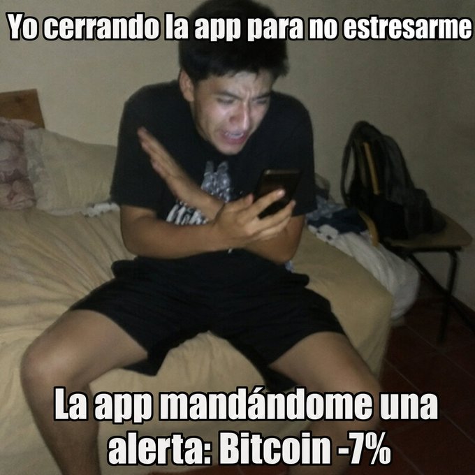 A Spanish-language meme showing a young man looking distressed on his phone with text reading 'Yo cerrando la app para no estresarme' and 'La app mandándome una alerta: Bitcoin -7%'.