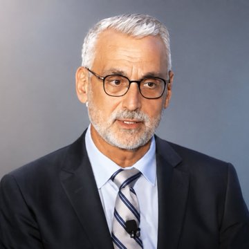 A serious-looking older man with a gray beard and glasses, wearing a dark suit, light blue shirt, and striped tie, speaks in an interview setting with a small lapel microphone attached to his jacket. The image appears to accompany commentary from Ripple CLO Stuart Alderoty regarding the upcoming procedural vote on the CLARITY Act in Congress.