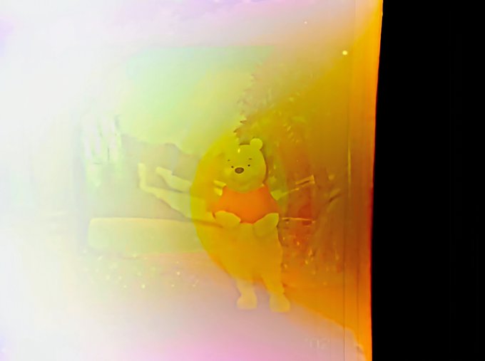 An image with a heavy yellow and rainbow color filter overlay, showing a person holding a stuffed Winnie the Pooh toy.