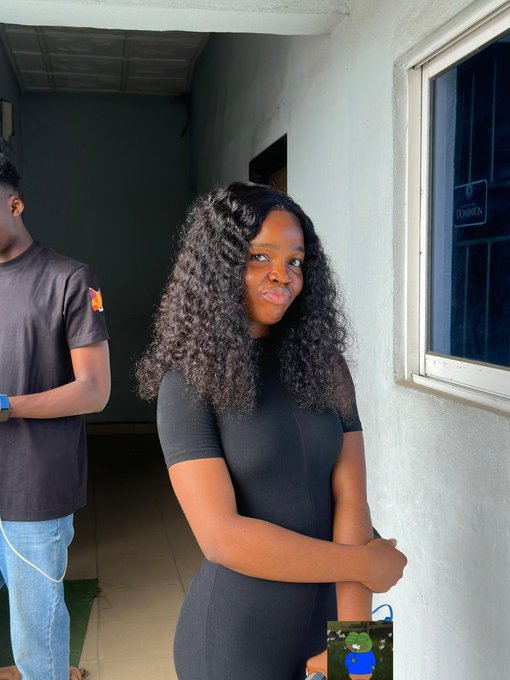 A woman with long, curly hair wearing a fitted black dress stands near a window with a "DAMON" label, smiling at the camera, while a man in a black t-shirt stands beside her. The post suggests she's attending a MetaMask event and plans to delete the photo soon, indicating a casual, behind-the-scenes moment from the gathering.