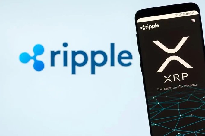 A smartphone displaying the Ripple XRP logo and 'The Digital Asset for Payments' text, with the Ripple logo visible in the background.