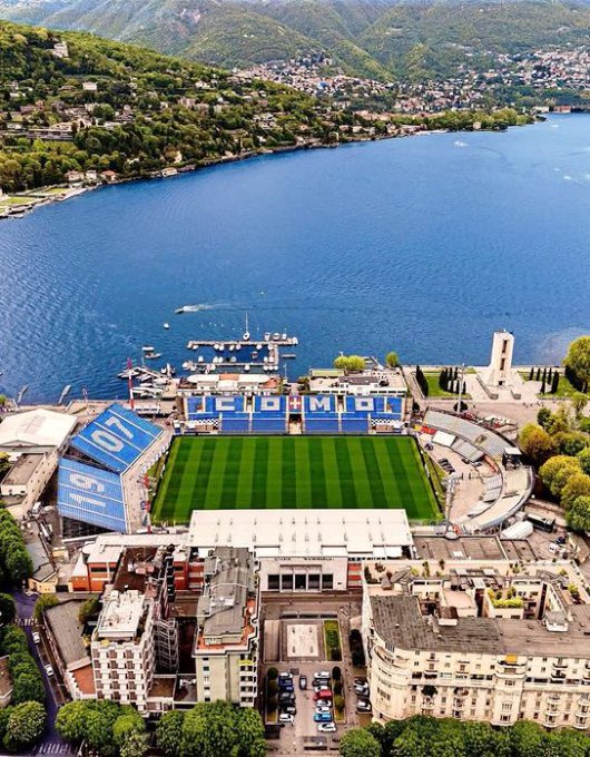 The image shows an aerial view of a large stadium with a river running through it, surrounded by buildings. The stadium has a soccer field within its premises, indicating that it could be a sports complex or a venue for sporting events. The surrounding area features several boats on the water and trees in the vicinity. The post about the sports complex also mentions that there is a website dedicated to the sports complex called "River4fun" and provides information about the site's content and features, such as real-time health updates, yield projections, and control over multiple assets.