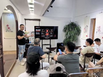 The image shows a group of people sitting around a table with a TV screen displaying an advertisement for AI, Web3, and Bitcoin. The room has white walls and a wooden floor, creating a cozy atmosphere. There are at least six people present in the scene, some sitting on chairs while others stand or sit on the floor. A potted plant is also visible near one of the attendees.

The advertisement features a man giving a presentation about AI and Web3 technology, with a focus on the future of these digital ecosystems. The group appears to be engaged in the discussion, possibly discussing the implications of this new wave of innovation or sharing their thoughts on the topic.