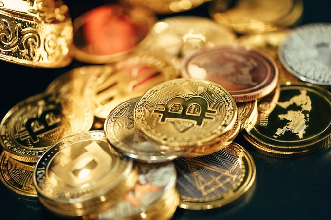 Gold-colored Bitcoin and other cryptocurrency coins are scattered across a dark surface, with the prominent Bitcoin "₿" symbol facing the camera, symbolizing the crypto collateral central to Kraken and Maple Finance's new onchain warehouse facility that enables institutional borrowers to access USDC liquidity backed by digital assets.