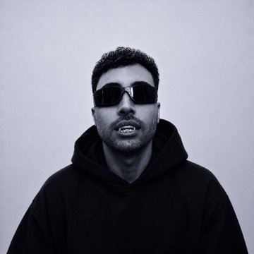 A black-and-white portrait of a man with short dark hair wearing black sunglasses and a black hoodie against a plain light background.