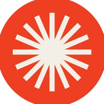 A minimalist graphic logo consisting of a white sunburst or starburst design centered inside a solid orange-red circle.