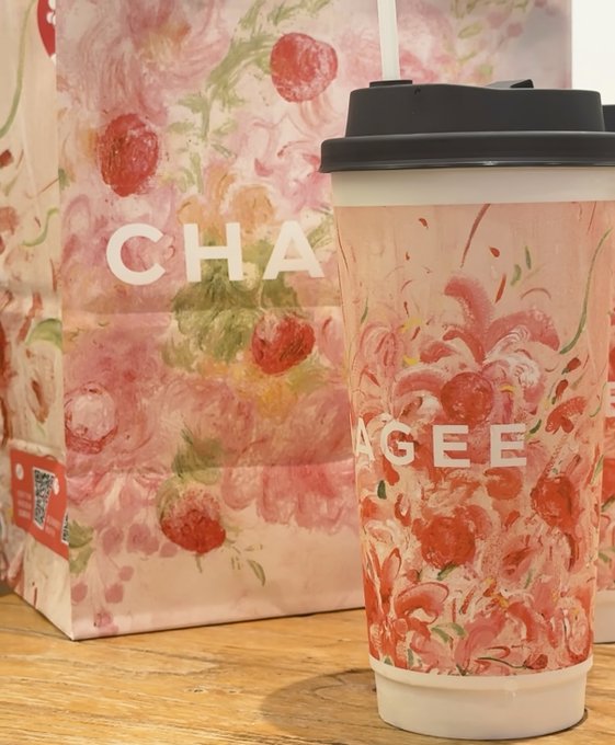A floral-patterned paper cup with "CHAGEE" branding and a matching pink floral shopping bag sit on a wooden surface, showcasing the brand's signature aesthetic. The post celebrates receiving this Chagee milk tea as a reward from CoinAnk, playfully hoping future account credits will arrive as promptly as the drink.