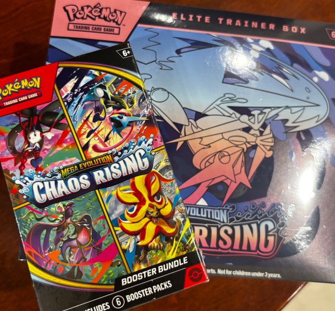 Two Pokemon trading cards, "Chaos Rising" and "Mega Evolution," are displayed on a wooden surface with the "Pokemon" logo.