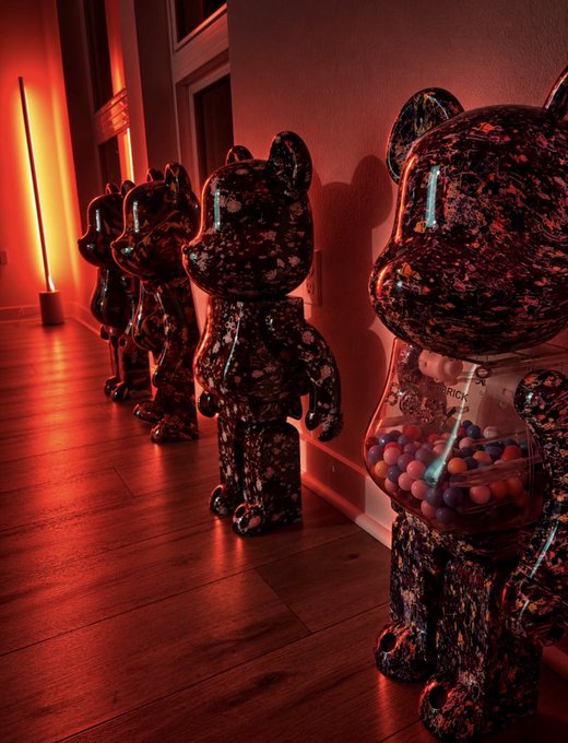 A row of large Bearbrick-style collectible figures in a glossy black and red marbled finish lined up in a hallway with red ambient lighting.