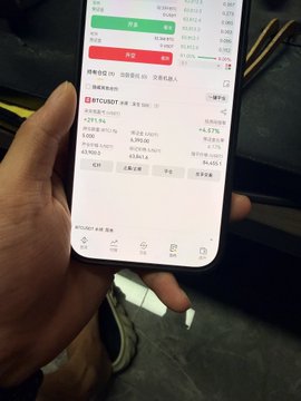 The image shows a smartphone screen displaying a cryptocurrency trading platform, specifically the BTC/USDT trading pair, with current prices and trading data. This directly relates to the post's discussion of opening a short position on BTC, indicating the user is likely using this platform to execute their trading strategy.
