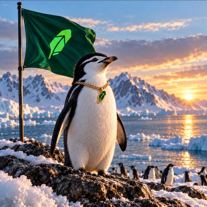 A penguin wearing a gold chain with a green pendant stands on a snowy rock holding a green flag with an upward arrow logo, set against a backdrop of icy mountains and a sunset.