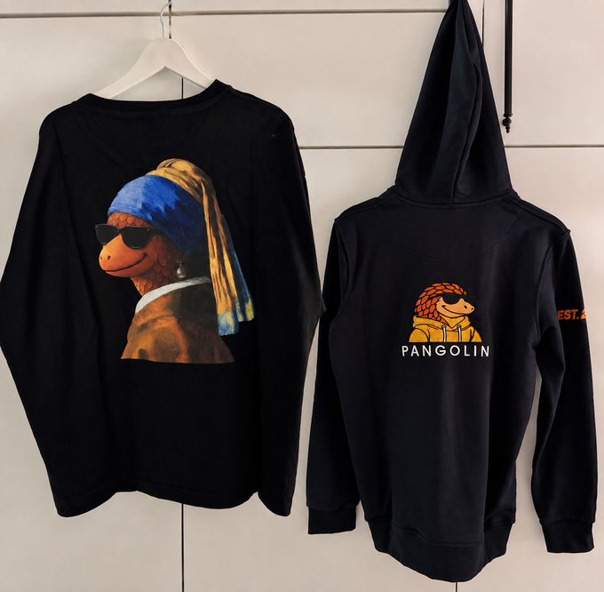 Two black hoodies displayed on hangers; the left one features a graphic of a character styled like the 'Girl with a Pearl Earring' wearing sunglasses and a blue/yellow headwrap, while the right one displays a 'PANGOLIN' logo with a cartoon pangolin character wearing sunglasses.