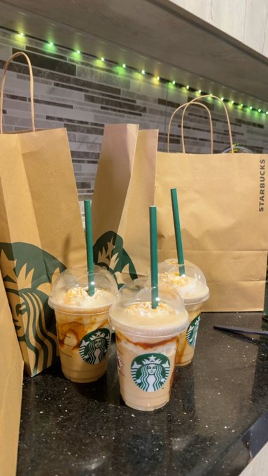 A Starbucks order with three caramel frappuccinos in branded cups and bags sits on a dark countertop beneath green string lights. The coffee shop receipt serves as a playful contrast to the post's message—unlike the verifiable history of public blockchains, this everyday transaction is just a fading paper bag of caffeine with no lasting audit trail.