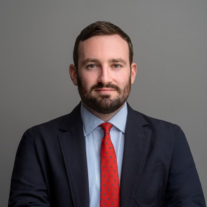 A professional headshot of Miller Whitehouse-Levine, a bearded man in a navy suit, light blue shirt, and red patterned tie, looking directly at the camera. The image accompanies news about his pessimistic outlook on the CLARITY Act's chances of passing before the midterms, as Solana Policy Institute CEO.