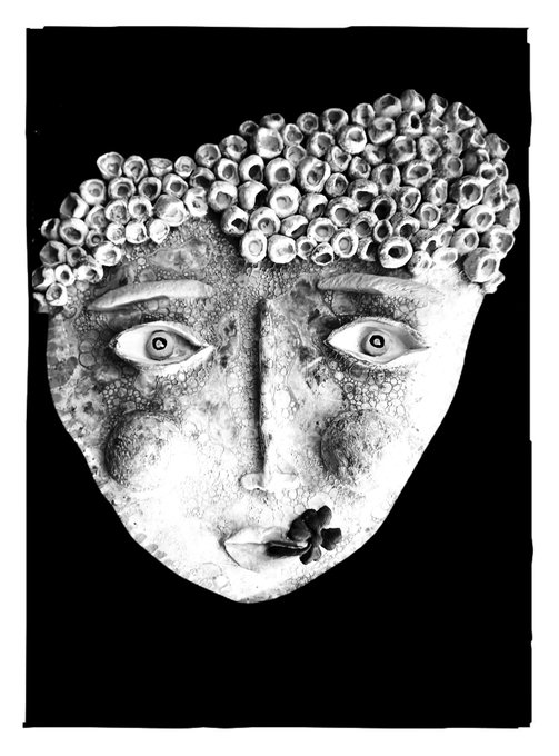 A black-and-white illustration of a textured face with stylized eyes, featuring a hairpiece made of barnacles or small shells.