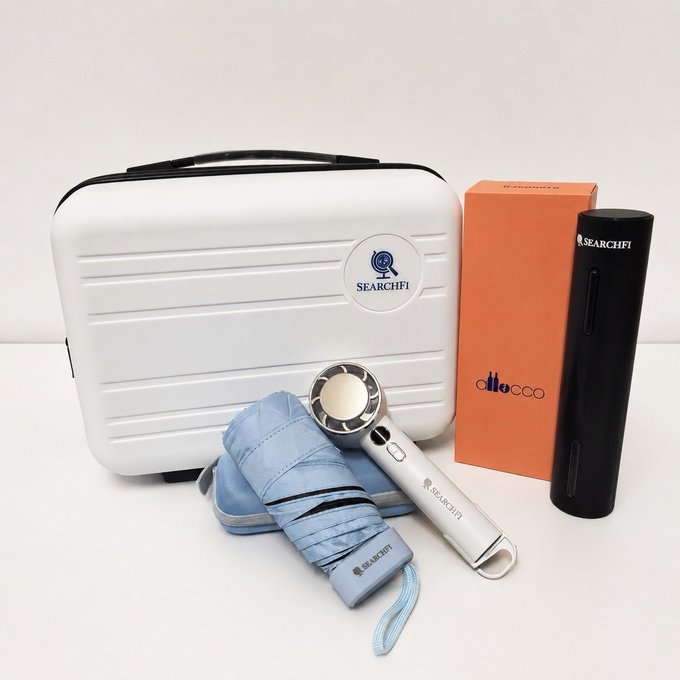 The image features two boxes, one white with blue text that says "SearchFi" and another black box with orange text that says "Ollie's". There are also two umbrellas - a blue one and an orange one - placed next to each other on a table. The objects in the image appear to be related to the SearchFi community, possibly as gifts or promotional items for members of the community who have recently gotten married.