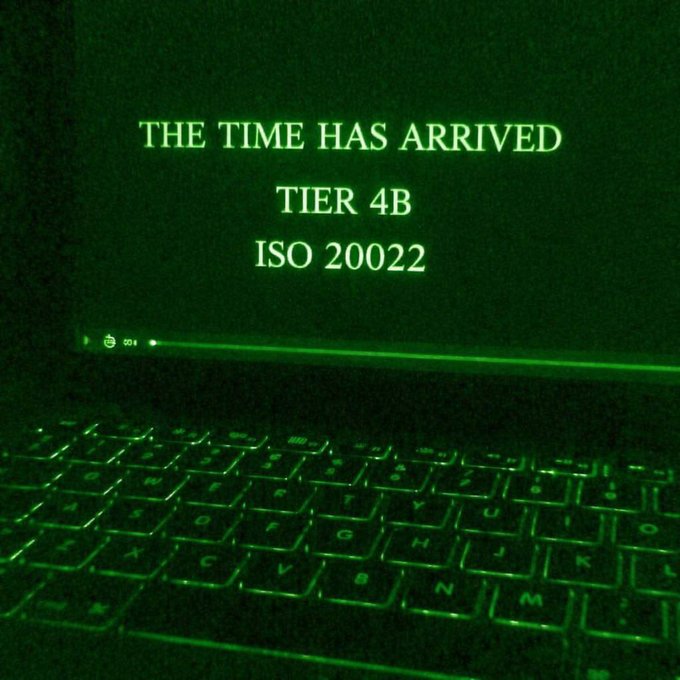 A laptop screen bathed in green light displays the message "THE TIME HAS ARRIVED TIER 4B ISO 20022," visually reinforcing the post's urgent "FINAL ALERT" about an ISO 20022 "execution phase" beginning. The eerie green glow and cryptic text evoke a clandestine, high-stakes signal consistent with the post's tone of an imminent, irreversible financial system shift.