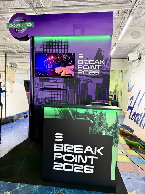 The image shows a large purple booth with a TV screen displaying a video of a city skyline, likely representing the BP26 event. The booth also features a sign that reads "BREAK POINT 2026" and another sign that says "London Edition". There is a small black box on top of the booth as well.