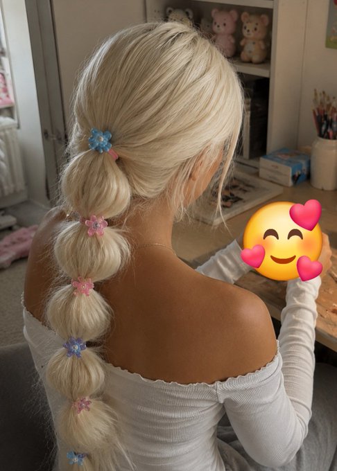 Back view of a person with long blonde hair styled in a bubble braid with colorful flower hair ties, with a smiley face emoji covering their face.