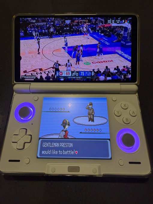 A handheld gaming device displays two screens simultaneously—the top showing a live NBA game with the Pistons trailing the Mavericks 69-75 in the 3rd quarter, while the bottom screen shows a Pokémon battle where "Gentleman Preston" wants to battle, perfectly capturing the multitasking of following sports markets while enjoying gaming.