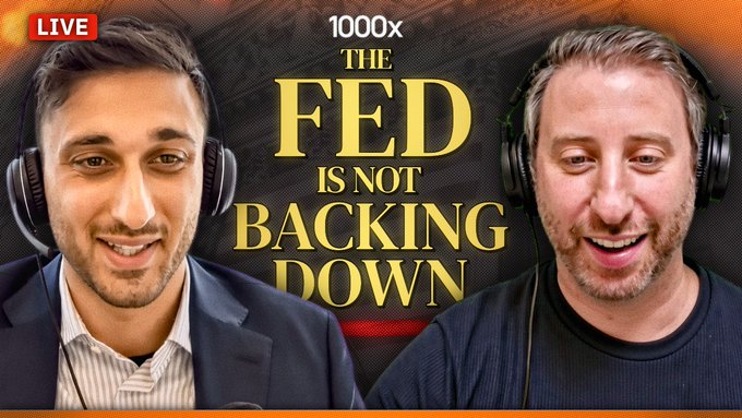 A thumbnail-style image for a live broadcast featuring two men wearing headphones, with text reading 'LIVE', '1000x', and 'THE FED IS NOT BACKING DOWN' in yellow and white lettering.