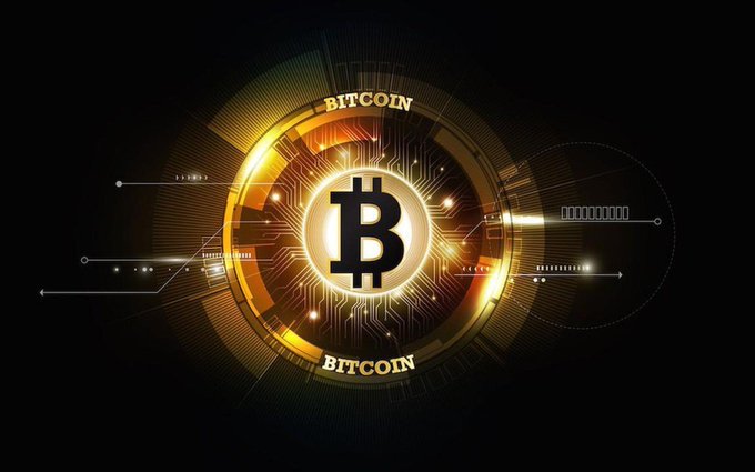 The image displays a glowing golden Bitcoin logo with the word "BITCOIN" encircling it, set against a dark background with digital circuit patterns, symbolizing cryptocurrency's decentralized architecture. This visual reinforces the post's theme about decentralized AI by illustrating how distributed networks—like Bitcoin's blockchain—redistribute value and power among many participants rather than central authorities, with each node contributing computing resources to the ecosystem.