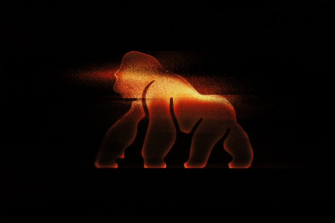 A glowing, particle-like silhouette of a gorilla stands against a black background, its fiery orange and yellow outline emanating a sense of primal strength. The image visually embodies the "APE" ticker, with the powerful ape figure symbolizing the iconic gorilla imagery associated with the APE cryptocurrency community.