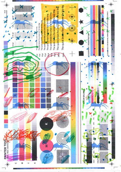A colorful printer test page showing color calibration bars, geometric patterns, and various test images including text, color gradients, and registration marks labeled 'PRINTER TEST' and 'REGISTRATION ALIGNMENT'.