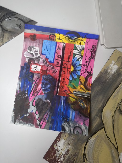 A vibrant, mixed-media artwork featuring a colorful collage of abstract elements, including flowers, figures, and a tic-tac-toe grid, displayed on a white surface alongside other artworks.
