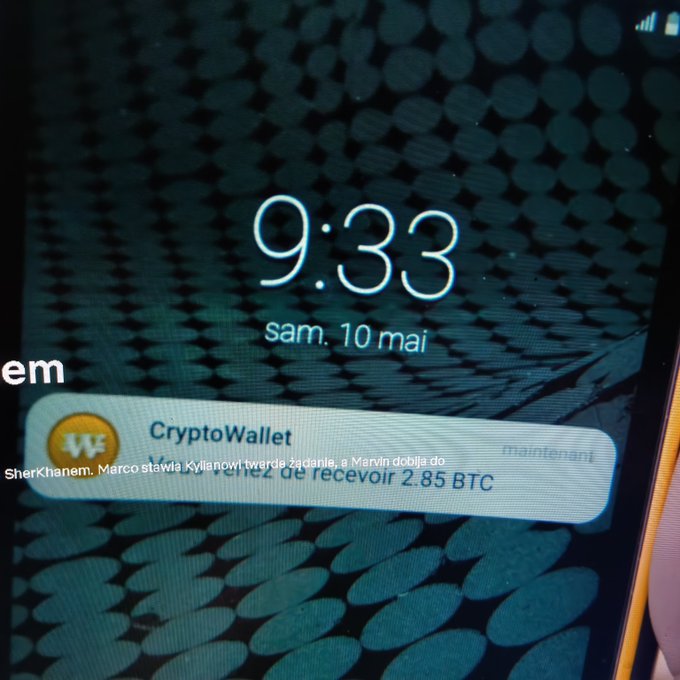 Smartphone lock screen showing the time '9:33' and date 'sam. 10 mai', with a CryptoWallet notification in French mentioning a transfer of 2.85 BTC.