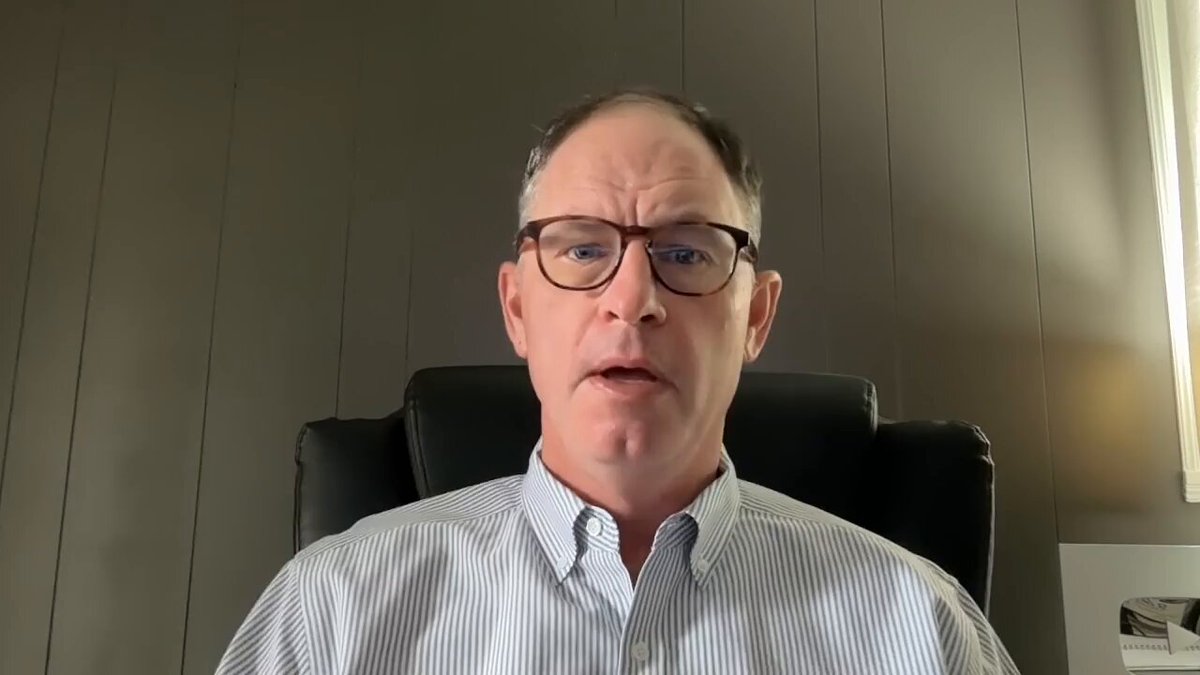The image shows a man wearing glasses sitting in an office chair, with his face clearly visible against a gray background. He appears to be giving a speech or presentation, as indicated by the presence of a computer monitor behind him. The caption at the bottom of the image reads "XRP Clarity Shock Revealed: The Institutional Green Light is HERE! (Includes Paid Promotion) Watch The Full Youtube Video Here: youtu.be/19-AHK-DGPQ".