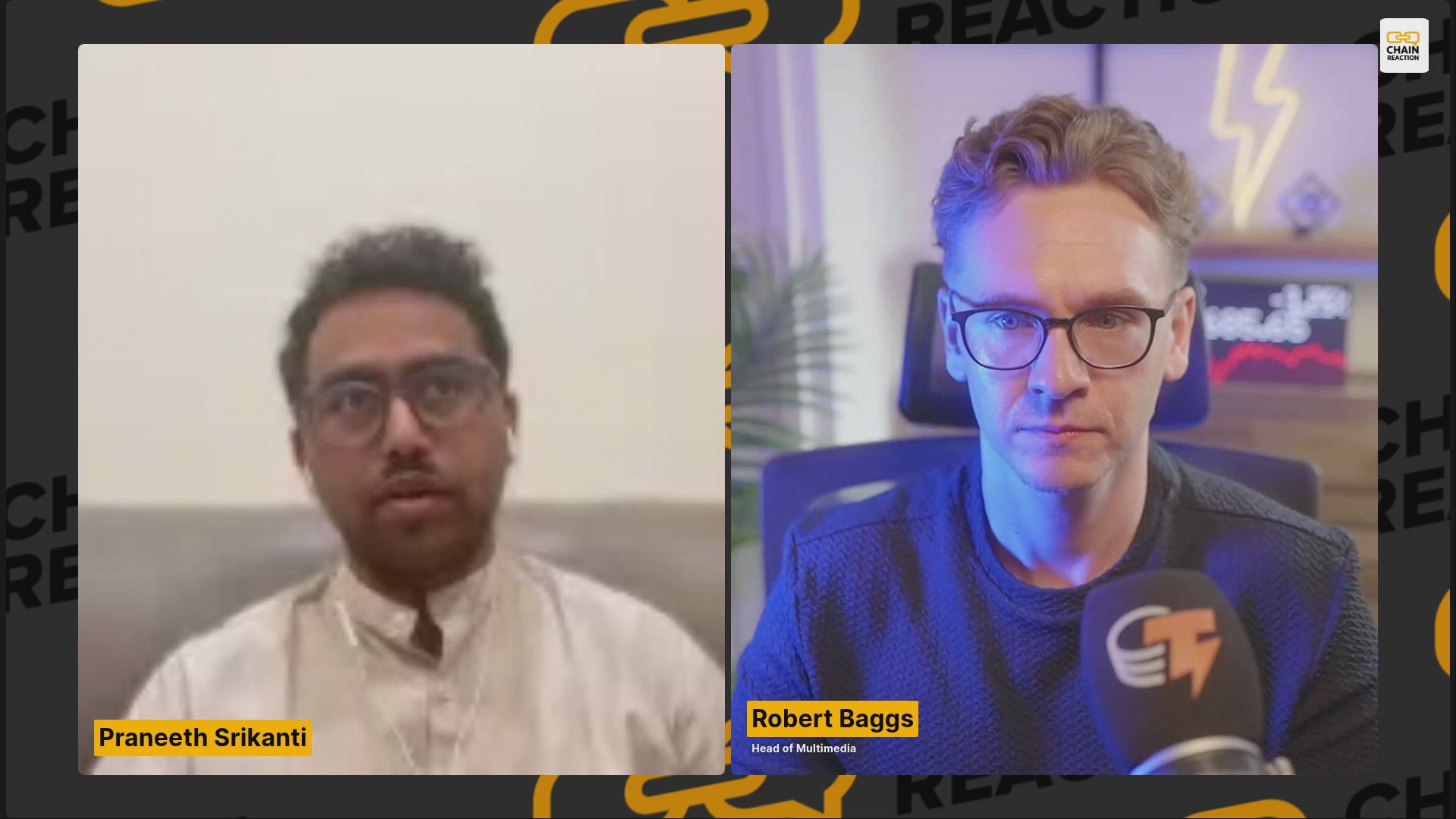 The image shows two men sitting behind microphones, likely participating in a podcast or interview. The background features a pattern of yellow and orange squares, which could be related to the content being discussed. The focus of the image is on the two individuals and their conversation, with no other objects or text present.
