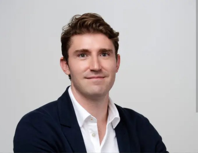 A professional portrait of a young man with curly brown hair, wearing a dark navy blazer over a white shirt, smiling subtly against a light gray background. The image pairs with a post highlighting him as Ivan Soto Wright, founder of MoonPay, who reportedly distributed over $300k to users as a "new month gift."