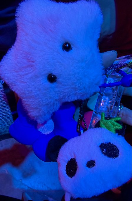 Close-up photos of plush panda keychains under blue lighting, highlighting their fluffy white fur, black bead eyes, and round black nose.