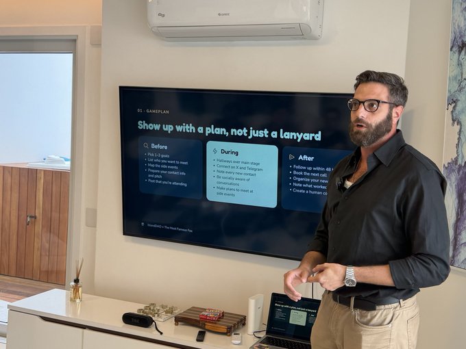 A presenter stands beside a large screen at a Solana/IslandDAO event, discussing a game plan titled “Show up with a plan, not just a lanyard,” with sections labeled “Before,” “During,” and “After.” The image illustrates the accompanying post’s claim that he led the first workshop in the history of the first Solana event in Brazil.
